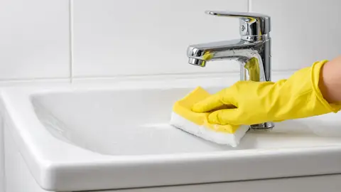 Gloved hand scrubbing a bathroom sink during a deep clean